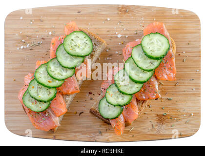 Sandwiches mit Brot, frischem Fisch und in Scheiben geschnittene Gurken mit Gewürzen auf Holz- Fach. Stockfoto