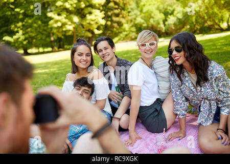 Freunde fotografieren im Sommer Picknick im Park Stockfoto