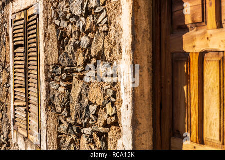 Geschlitzte Fensterläden aus Holz auf einem alten Steinhaus, in dem Dorf Chirche, Guia de Isora, Teneriffa, Kanarische Inseln, Spanien Stockfoto