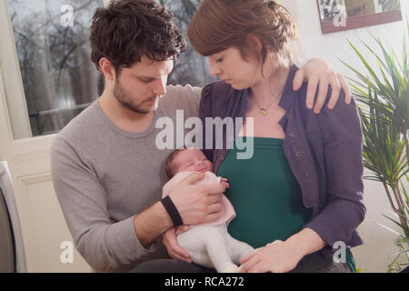 Junge Eltern halten ihre neugeborene Tochter im Arm, das Art ist 12 Tage alt | junge Eltern ihr neugeborenes Baby in ihren Armen halten - das Baby ist 12. Stockfoto