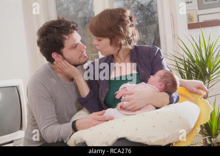 Junge Eltern halten ihre neugeborene Tochter im Arm, das Art ist 12 Tage alt | junge Eltern ihr neugeborenes Baby in ihren Armen halten - das Baby ist 12. Stockfoto