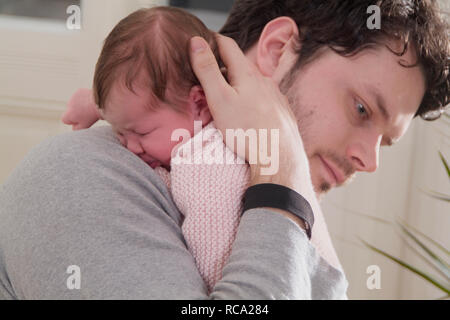 Junger hält seine neugeborene Tochter im Arm, das Art ist 12 Tage alt | junge Vater sein neugeborenes Baby in seinen Armen halten - das Baby ist 12 Tage alt Stockfoto