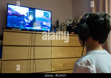 Ein kleiner Junge spielt der computer spiel Fortnite auf einem Spiele in einem Schlafzimmer Konsole Stockfoto