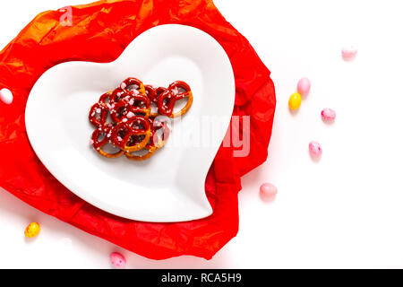 Idee für Valentine behandelt Brezel dip-Schokolade in Herzform aus Keramik Platte auf weißem Hintergrund mit Kopie Raum Stockfoto