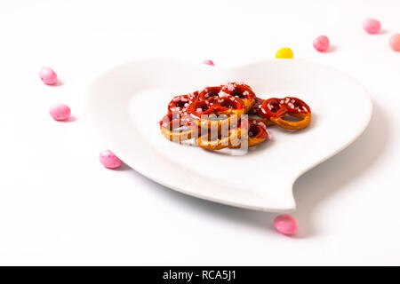 Idee für Valentine behandelt Brezel dip-Schokolade in Herzform aus Keramik Platte auf weißem Hintergrund mit Kopie Raum Stockfoto