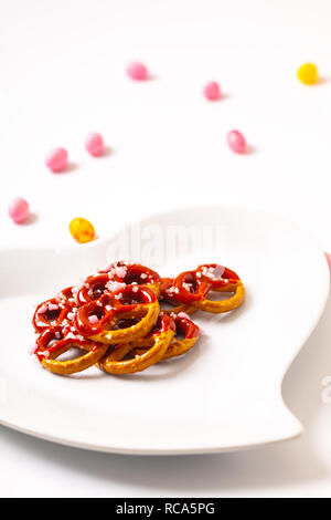 Idee für Valentine behandelt Brezel dip-Schokolade in Herzform aus Keramik Platte auf weißem Hintergrund mit Kopie Raum Stockfoto