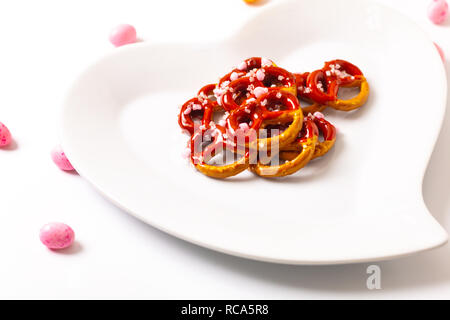 Idee für Valentine behandelt Brezel dip-Schokolade in Herzform aus Keramik Platte auf weißem Hintergrund mit Kopie Raum Stockfoto