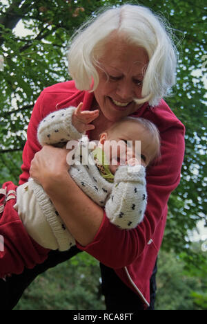 Oma hat Enkelkind im Arm | Großmutter trägt ihre Enkelin auf dem Arm Stockfoto
