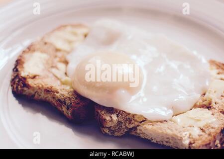 Die perfekt pochierte Eier auf Gesäte gebuttertem Toast braun-Filter angewendet Stockfoto