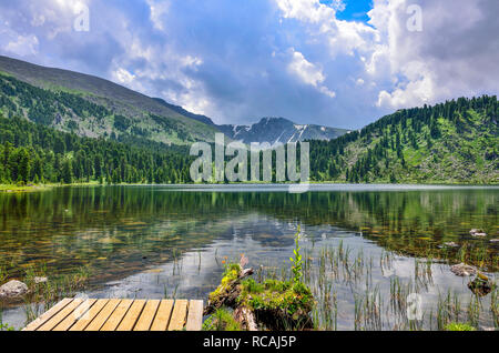 Eine aus sieben sauberste Berg Karakol Seen mit hölzernen Plattform auf der linken Seite, am Fuße des Bagatash Pass, Altai Gebirge, Russland. Nadelholz für Stockfoto