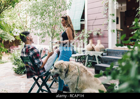 Junges Paar und ihr Hund sitzt lächelnd im Garten liegen in der Nähe ihrer Häuser Stockfoto