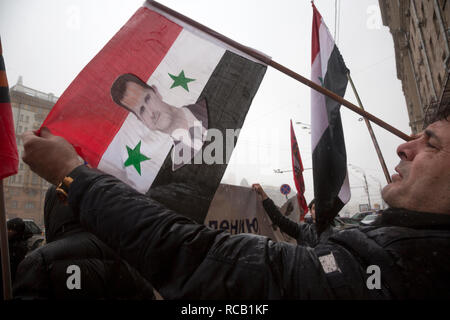 Syrische Flüchtlinge Holding eine syrische Flagge mit einem Porträt von Präsident Bashar al-Assad, der vor der US-Botschaft im Zentrum von Moskau, Russland Stockfoto