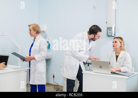 Heiteres medizinisches Team in der zahnmedizinischen Büro diskutieren sie über Praxis und Prüfung der Liste der Patienten. Stockfoto