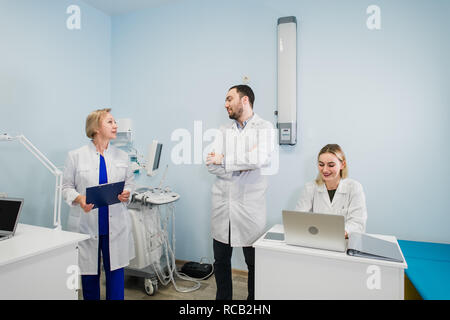 Heiteres medizinisches Team in der zahnmedizinischen Büro diskutieren sie über Praxis und Prüfung der Liste der Patienten. Stockfoto
