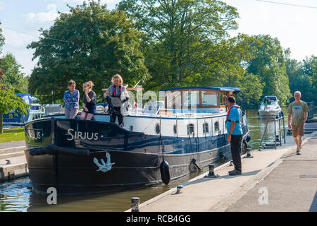 Schleusenwärter beobachten Barge und Cruiser eingabe Hurley Sperren im Sommer auf der Themse in Hurley in der Nähe von Maidenhead, Berkshire, Großbritannien Stockfoto