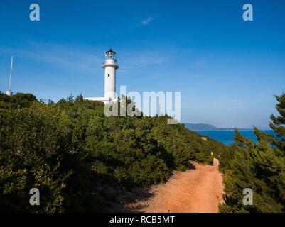 Schmutzige Straße entlang grüne Landschaft zu wunderschönen glänzenden weißen Leuchtturm am Ende einer schönen Insel Cape mit Blick auf das Meer im Hintergrund sichtbar führenden Stockfoto