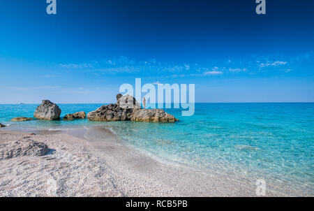 Die beeindruckende Aussicht auf das kristallklare blaue Wasser milchig an exotischen Stränden Lefkada mit Frau mit Blick aufs Meer Horizont Stockfoto