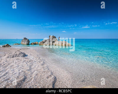 Die beeindruckende Aussicht auf das kristallklare blaue Wasser milchig an exotischen Stränden Lefkada mit Frau mit Blick aufs Meer Horizont Stockfoto
