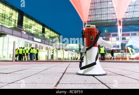 15 Januar 2019, Bayern, München: ein Megaphon steht auf dem Boden vor Terminal 2 am Flughafen, und Mitarbeiter haben auch in einem warnstreik vor dem Gebäude versammelt. Verdi hat für einen Warnstreik durch die Waren der Flughafen und die Kontrolle der Mitarbeiter Mitarbeiter genannt. Foto: Tobias Hase/dpa Stockfoto