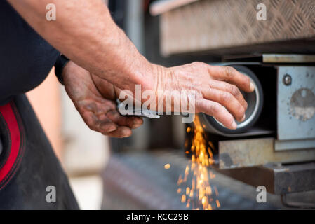 Metallverarbeitende Industrie: Finishing Metallbearbeitung auf horizontalen Oberflächen grinder Maschine mit Funkenflug. Stockfoto