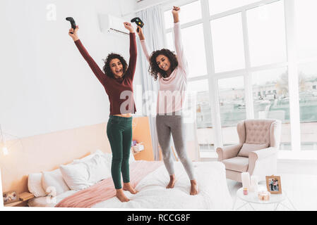 Curly glückliche Mädchen glücklich Springen auf Doppelbett Stockfoto