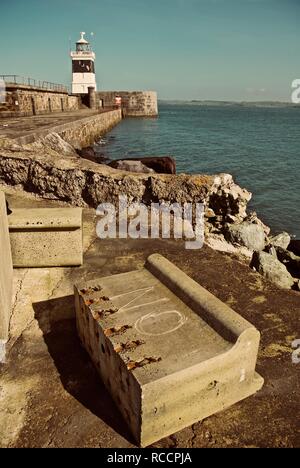 Nicht auf einem Betonklotz auf dem Holyhead Wellenbrecher Wellenbrecher gemalt mit dem Leuchtturm im Hintergrund, Holyhead, Anglesey, North Wales, UK Stockfoto