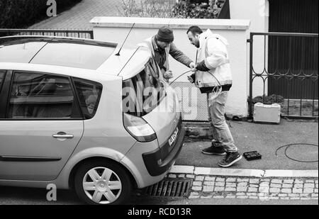 PARIS, Frankreich, 19.MÄRZ 2018: Team in der Nähe von offenen Abwasser Schacht Loch mit Kabel auf Spule Schieber - Telekommunikation Internet Provider Unternehmen, die an der Durchführung der Lichtwellenleiter - Schwarz und Weiß Stockfoto