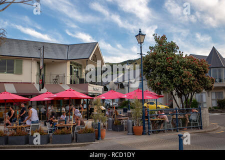 Akaroa Halbinsel, Banken, Neuseeland - 5. Januar 2019: Touristen speisen Sie unter den Sonnenschirmen am Wharf Restaurant an einem heißen Sommerabend Stockfoto