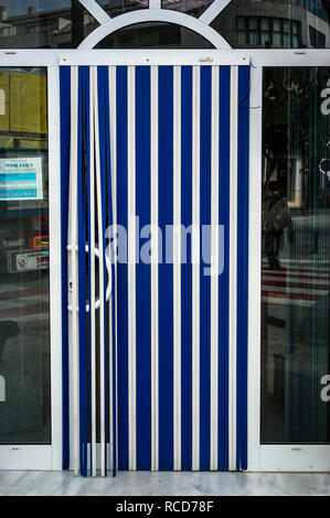 Blau und Weiß Gestreifte Kunststoff vertikale Klappe Bildschirm auf einer französischen Haus Tor Eingang Stockfoto