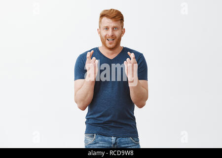 Kommen Kerle, die ich an sie glauben. Stattliche männliche redhead männliches Modell nervös mit gekreuzten Fingern, in die Kamera starrt, wichtigen Match und die Wette zu gewinnen, in der Hoffnung, Stockfoto