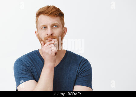 Hmm Wir denken. Portrait von konzentrierte sich kreative und intelligente gut aussehende männliche Stratege mit roten Haaren, stehend in nachdenklicher Pose, reibt Bart und zur Seite schauen beim Denken, bis der Plan im Kopf Stockfoto