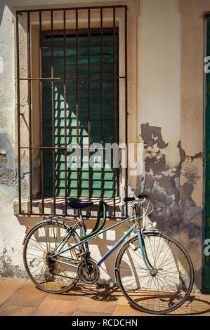 Pushbike außerhalb einer alten französischen Haus, Bike lehnte sich auf einem grünen Fensterläden Fenster mit Sicherheit Bars Stockfoto