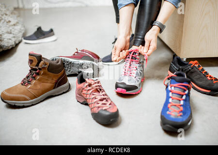 Frau, die versucht, verschiedene trail Schuhe für Wandern im Sportgeschäft, Nahaufnahme mit kein Gesicht Stockfoto
