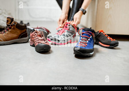 Frau, die versucht, verschiedene trail Schuhe für Wandern im Sportgeschäft, Nahaufnahme mit kein Gesicht Stockfoto