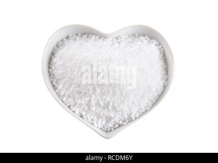 Herzförmige Schale mit Fleur de Sel Salz isoliert auf Weiss auf der Oberfläche durch Verdampfung von Meerwasser gebildet Stockfoto