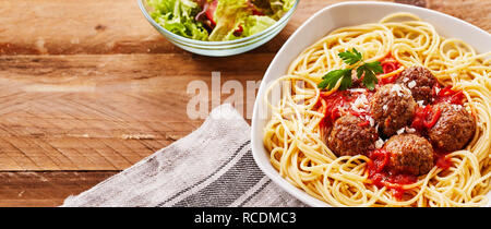 Mit der würzigen mini Frikadellen mit spaghetti Pasta oder Nudeln auf rustikalem Holz mit Salat und Kopieren der Platz in einem Panorama banner Stockfoto