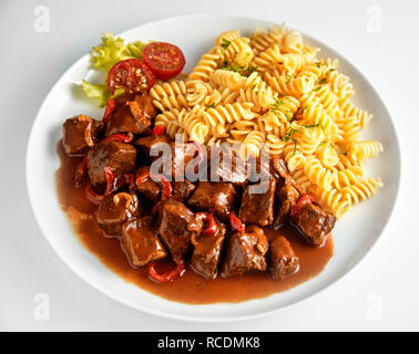 Rotwild Rehgulasch mit Fusilli auf einem weißen Teller hohen Winkel für ein Menü oder eine Werbung gesehen Stockfoto