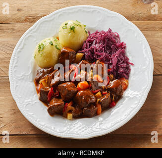 Platte von Rotwild oder Hirschgulasch mit geschredderten Rotkohl und Klöße für einen leckeren Deutschen oder Bayerischen Mahlzeit im quadratischen Format Stockfoto