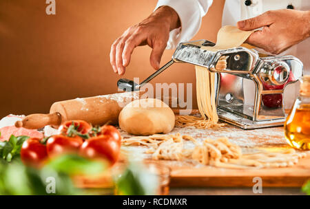 Der Küchenchef bereitet Spezialitäten Hausgemachte Pasta nudeln Bestehen der Teig durch das Werkzeug in eine Enge, das an der Maschine Stockfoto