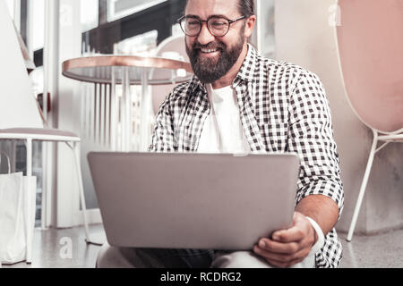 Lächelnder Mann, der das Notebook während der Arbeit Stockfoto