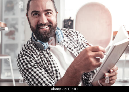 Lächelnder Mann mit seinem Notebook bei der Arbeit Stockfoto