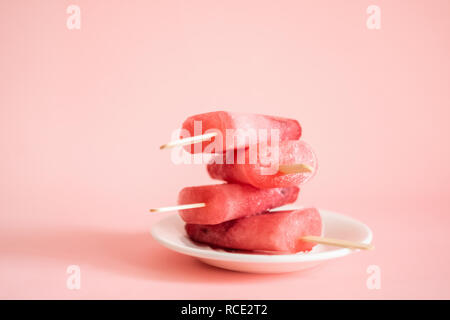 Berry oder Eis am Stiel auf einem weißen Teller serviert. Rosa Eis auf einem rosa Hintergrund. Vorderansicht horizontalen Rahmen. Kopieren Sie Platz. Stockfoto