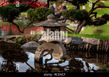 Münzen in einem kleinen japanischen Teich mit Reflexionen Stockfoto