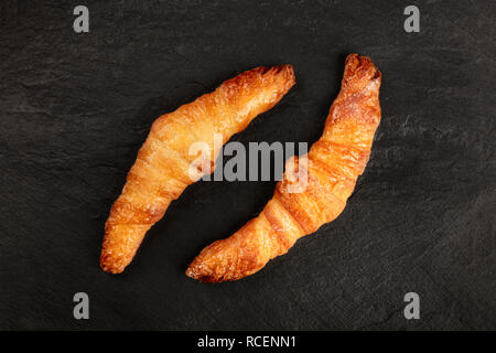 Zwei Croissants auf schwarzem Hintergrund, geschossen von oben, mit Kopie Raum Stockfoto