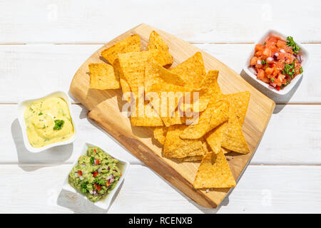 Auswahl an mexikanischen Soßen - Salsa, Guacamole, Käse Sauce und Zutaten, weiß Holz Hintergrund Stockfoto