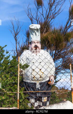 Mannequin Kochen wie ein Garten Ornament im Garten hinter einem Stacheldrahtzaun. Stock Bild. Stockfoto