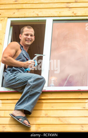 Männliche professional in Latzhosen putzt die Fenster im Haus Stockfoto