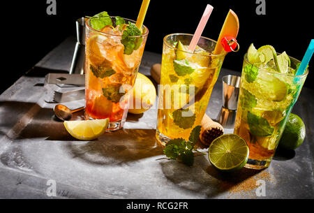 Frische tropische Früchte Cocktails mit Minze serviert auf Crushed Ice in hohe Gläser mit Strohhalm und Zutaten wie Kiwi, Limette und Zitrone mit Stockfoto