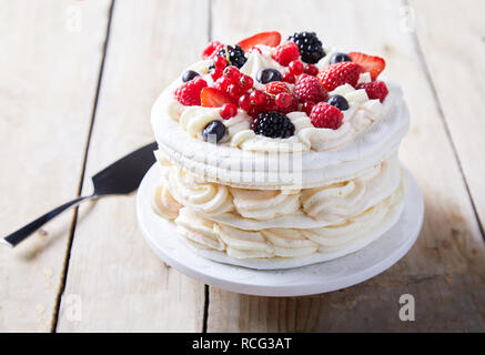 Gourmet pavlova Kuchen mit frischen berry Topping und Schichten von Sahne und meringue auf einem Teller serviert mit einem Spachtel in der Nähe zu sehen. Stockfoto