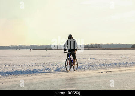 Man Radfahren über einen zugefrorenen See in den Niederlanden. In diesem Februar Temperaturen in den Niederlanden ein außergewöhnlich niedriges - 20 C gefallen Stockfoto